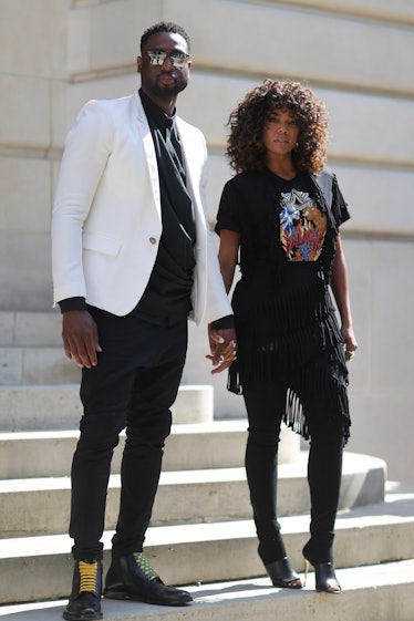 Gabrielle Union in a black shirt with print and a black skirt and Dwyane Wade in a white blazer and ...
