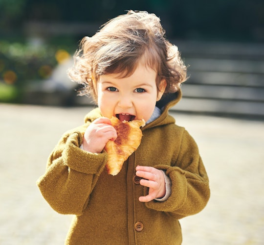 A little kid eating a croissant