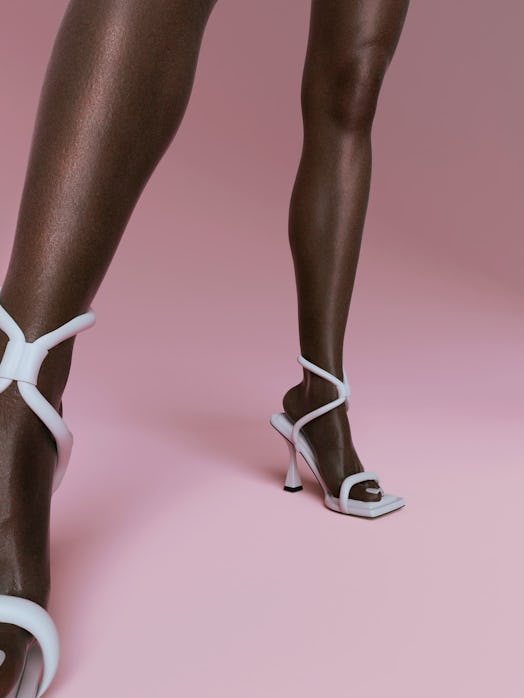 A closeup of a model's feet in white Hanifa shoes