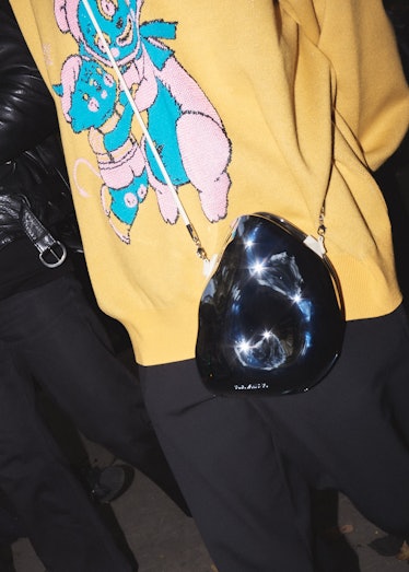 Close up detail of a cartoon print sweater with sculptural purse at Paris Fashion Week.