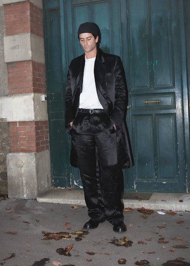 Showgoer at Paris Fashion Week wears black satin suit. 