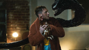 Eddie holds Venom's pet chicken, threatening Venom to stop asking about eating brains.