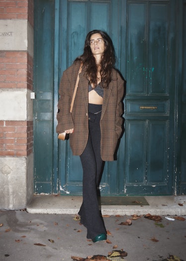 Showgoer at Paris Fashion Week wears oversized brown jacket and black pants.