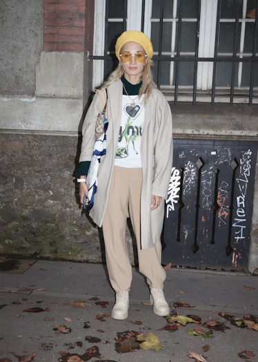 Showgoer at Paris Fashion Week in tan pants and jacket and yellow beret. 