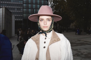 Street style at Paris Fashion Week: Showgoer wears pink hat with scarf and white sweater.