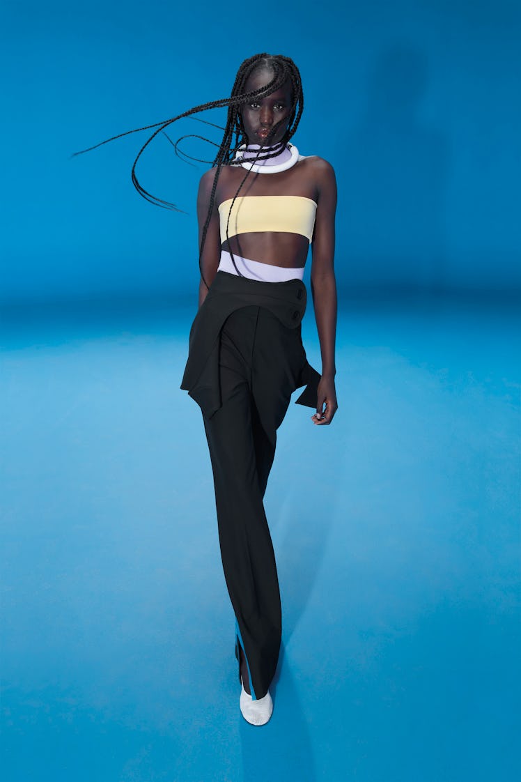 Model wears Nina Ricci spring 2022 collection at Paris Fashion Week, a yellow bandeau top and black ...