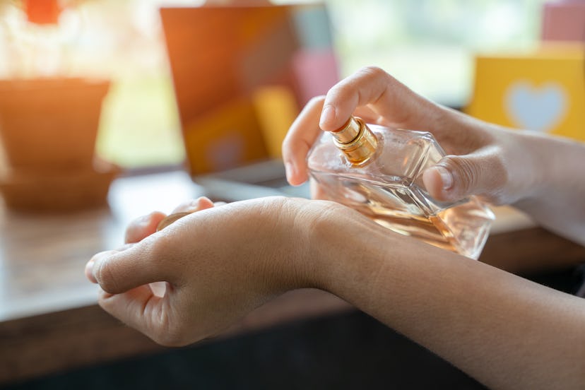 Woman spraying wrist with perfume