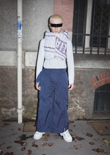 Showgoer at Paris Fashion Week wears wraparound sunglasses and blue parachute pants.