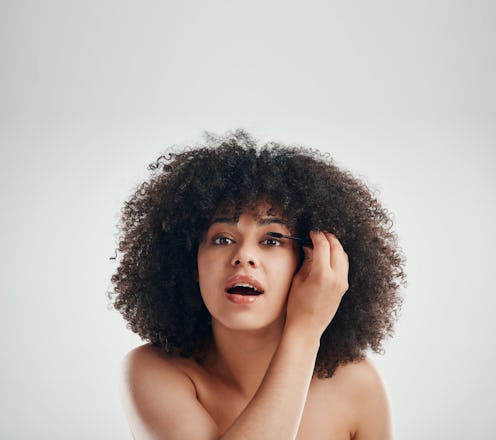 Young woman applying mascara to her lashes