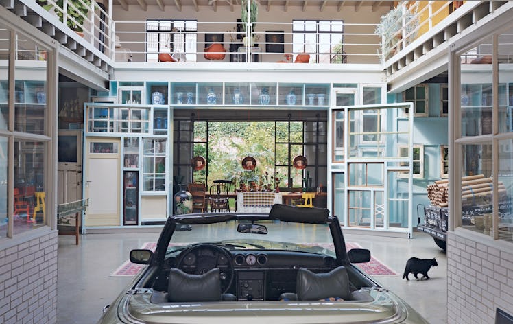 the atrium of a modern house in the netherlands, with a car parked in the center and art objects all...