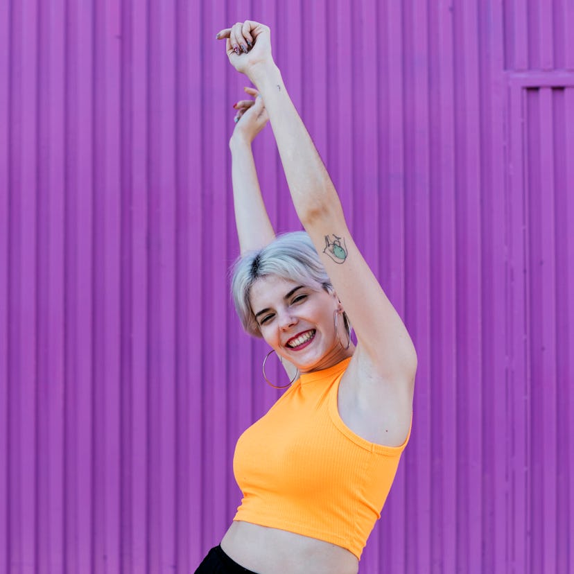 Young woman with her arms in the air the week of October 25, 2021, having the best time per her zodi...