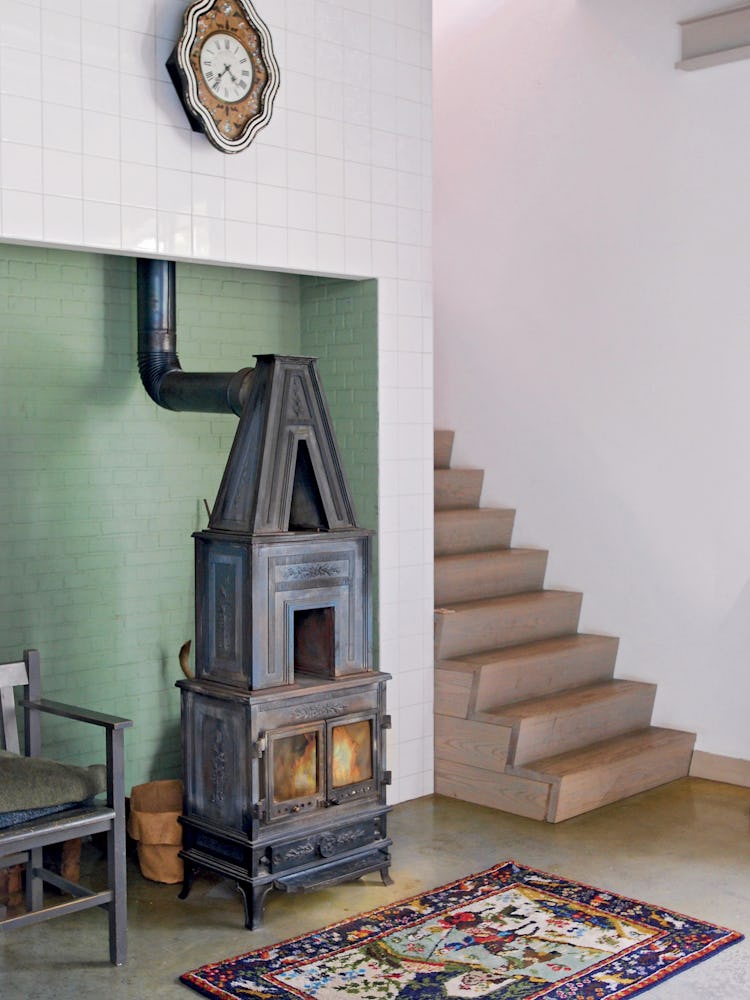 a wood burning stove at the bottom of a modern staircase