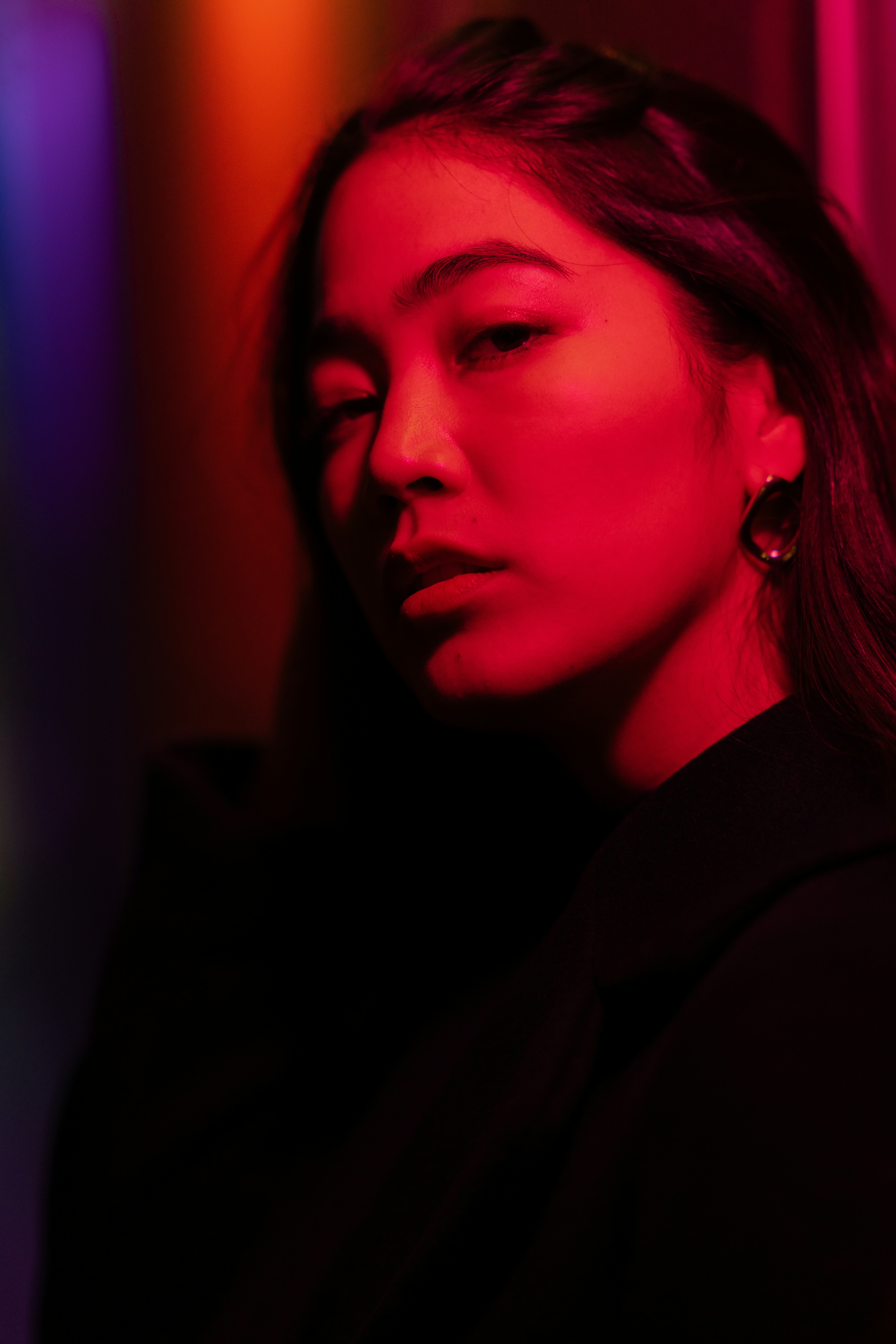 Young woman lit by red neon light as Jupiter retrograde 2021 comes to an end.