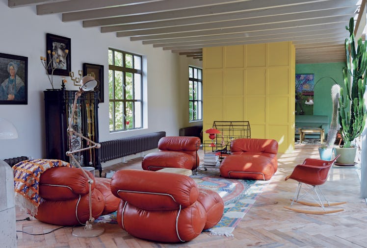 a living room with a yellow wall and bulbous red leather couches