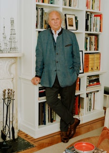 Graydon Carter leaning against a bookshelf in his office