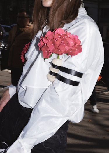 Showgoer wears flower accessories outside Miu Miu spring 2022 show at Paris Fashion Week.