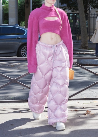 Showgoer wears pink sweater and puffer pants outside Miu Miu spring 2022 show at Paris Fashion Week.