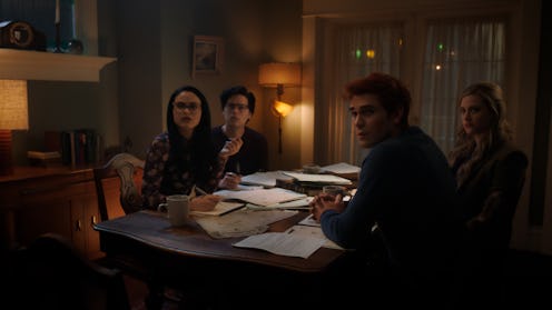 The core four of Riverdale sits at a table looking towards the camera in a scene from Riverdale Seas...