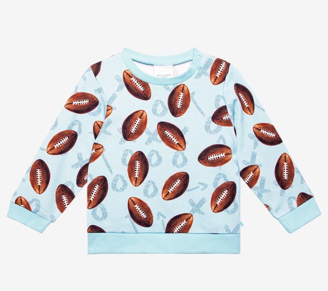 Image of a child-size blue sweatshirt with brown footballs on it. 