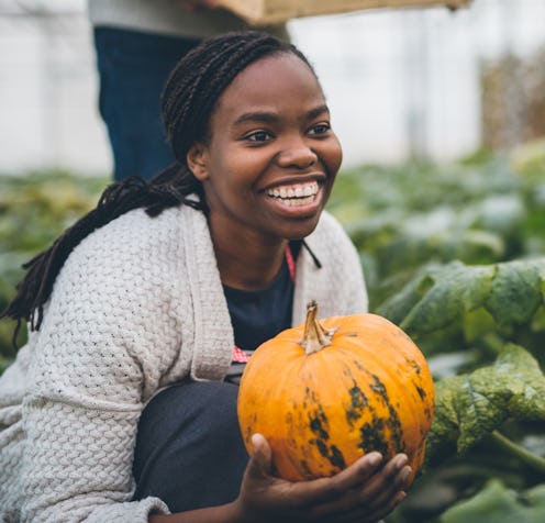 A woman picks a pumpkin and looks really happy about it
