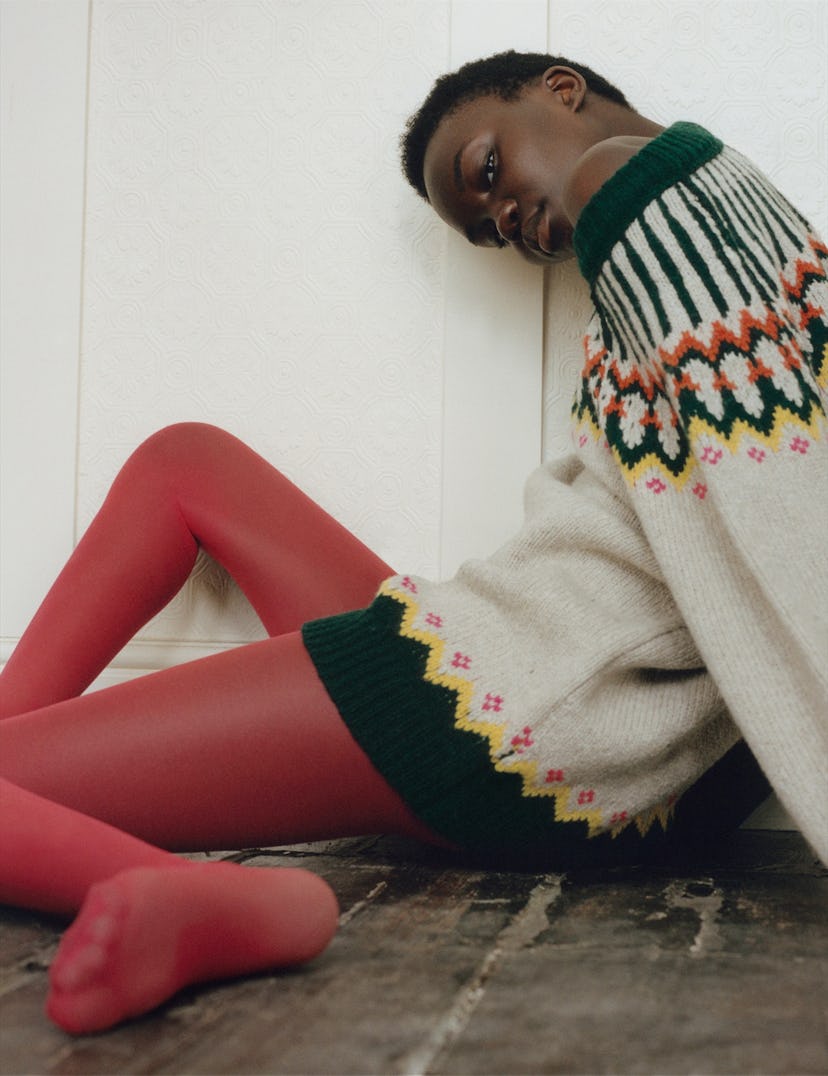 a woman in a fair isle sweater and red tights sitting on the floor