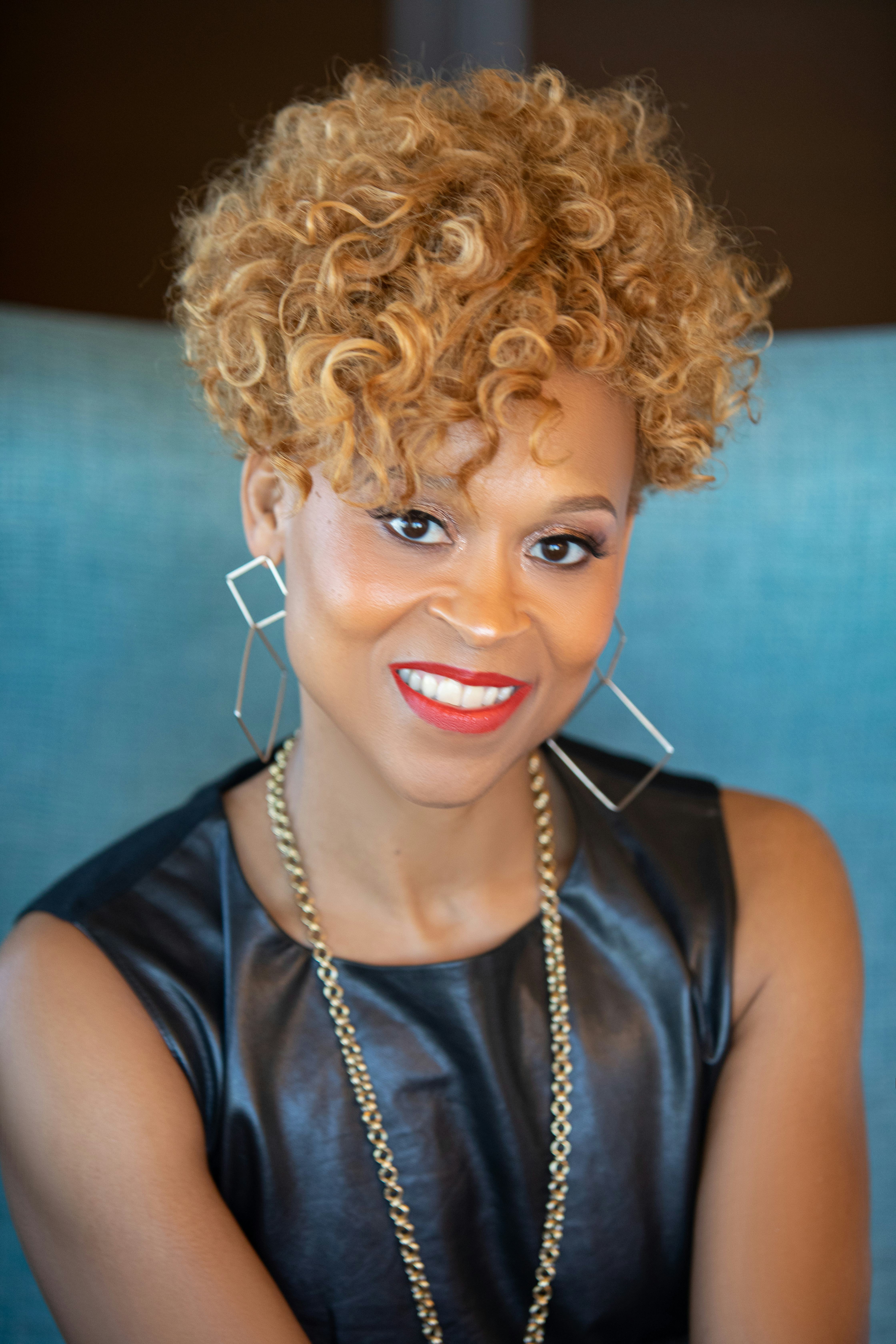A portrait of Essi Eggleston Bracey in a leather top, chain necklace and square hoops