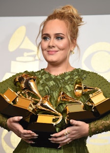 Adele holding an armful of Grammy awards