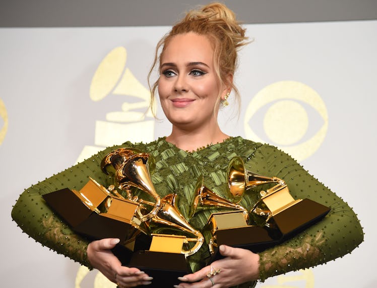 Adele holding an armful of Grammy awards