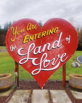 A heart-shaped sign at the entrance of a hotel that says "you are entering the land of love"