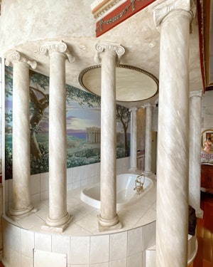 A bath tub with poles around it resembling those or the Roman Empire