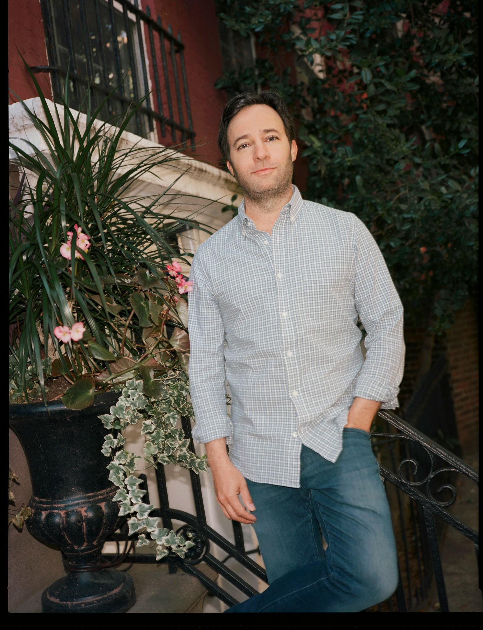 Danny Strong leaning against a staircase outdoors