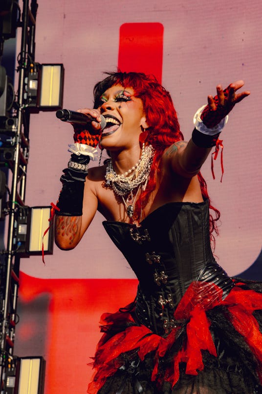 Rico Nasty performing wearing a Halloween costume: black corset and red lace in combination with a l...