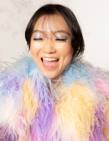 Olivia Cheng in a feathered coat and smiling.
