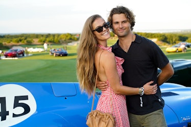 Nina Agdal in a white-red check dress and Jack Brinkley-Cook in a black shirt and khaki trousers pos...