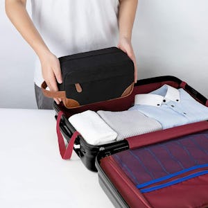 A man packing clothes and using the Vorspack Toiletry Bag Hanging Dopp Kit