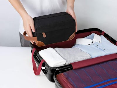 A man packing clothes and using the Vorspack Toiletry Bag Hanging Dopp Kit