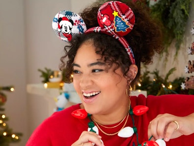 A woman wears some Mickey ears and a light up Christmas necklace from Disney's 2021 holiday merch co...