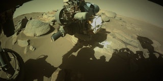 An image captured by the Perseverance rover's front camera showing Martian rock with the rover's arm...