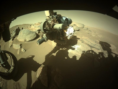 An image captured by the Perseverance rover's front camera showing Martian rock with the rover's arm...