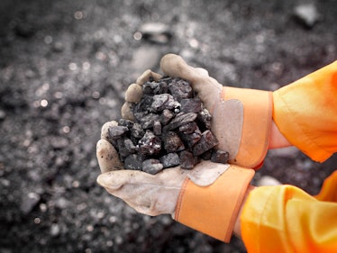 Coal worker holds coal in outstretched 