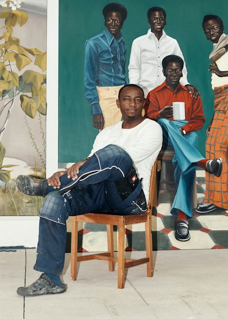 Peter Uka in his studio in Cologne, Germany with his paintings behind him 