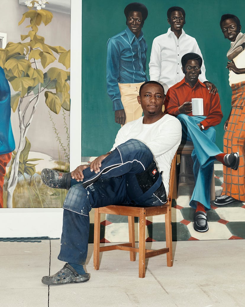 Peter Uka in his studio in Cologne, Germany with his paintings behind him