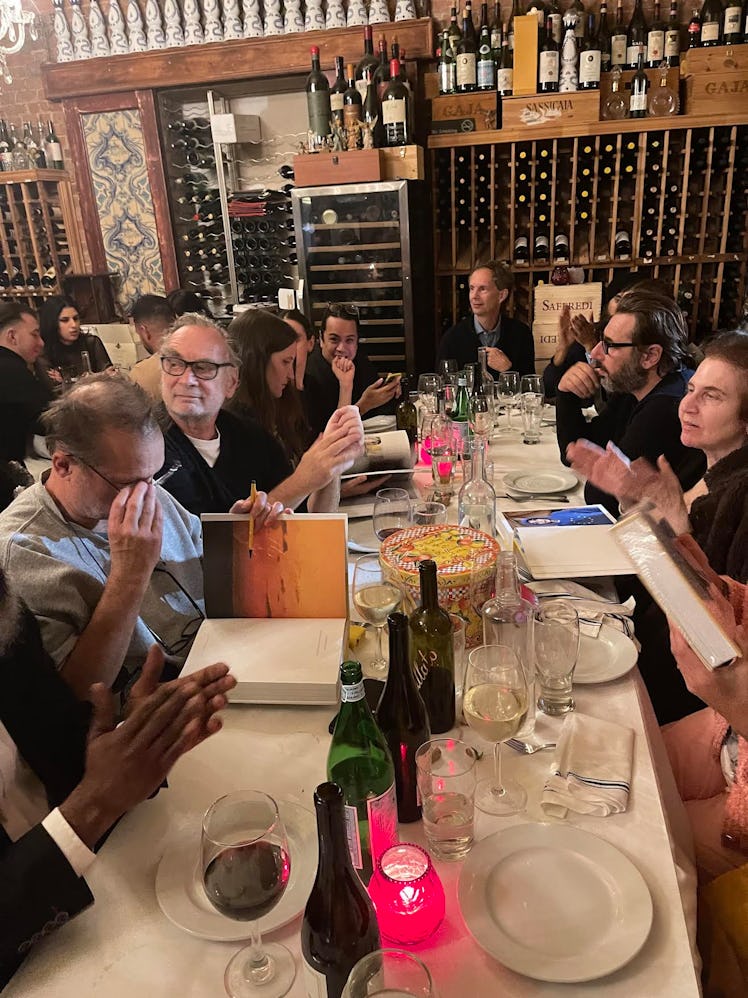 Guests sitting at a table of a dinner hosted by Juergen Teller, Dovile Drizyte, and Sara Moonvesests...