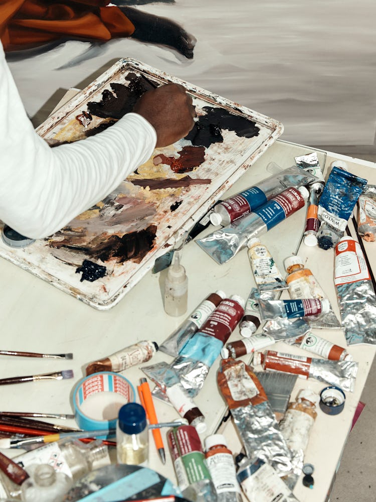 Peter Uka mixing colors for a painting in his studio 