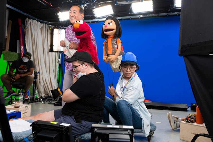 Two puppeteers crouch under Elmo and Ji-Young puppets as they work alongside longtime "Sesame Street...