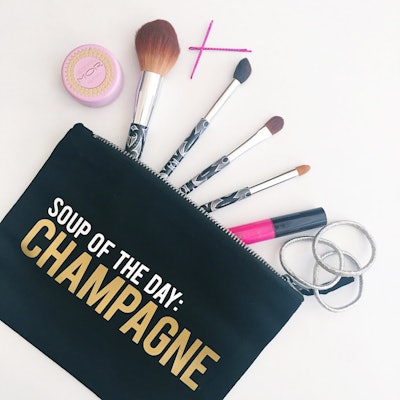 Black makeup bag that says "Soup of the day: CHAMPAGNE"