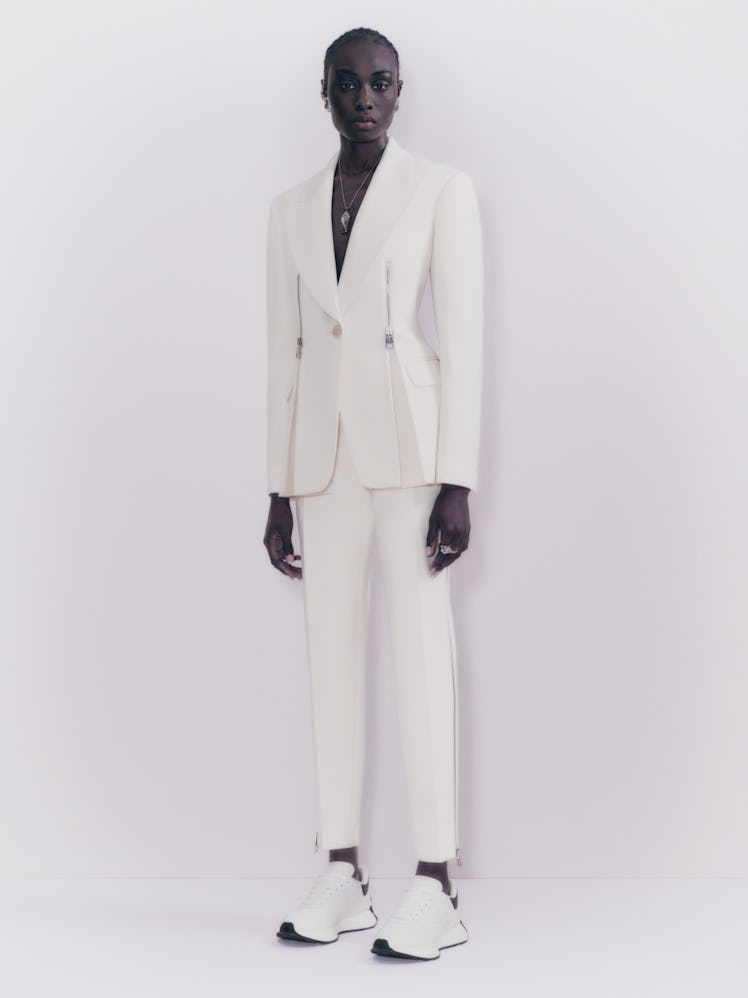 Model posing in a white suit from Alexander McQueen