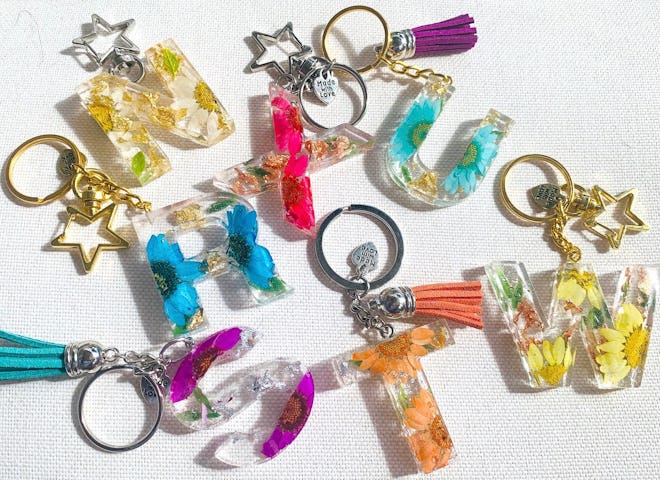 Several keychains laying on a table, each with a letter initial and charms attached