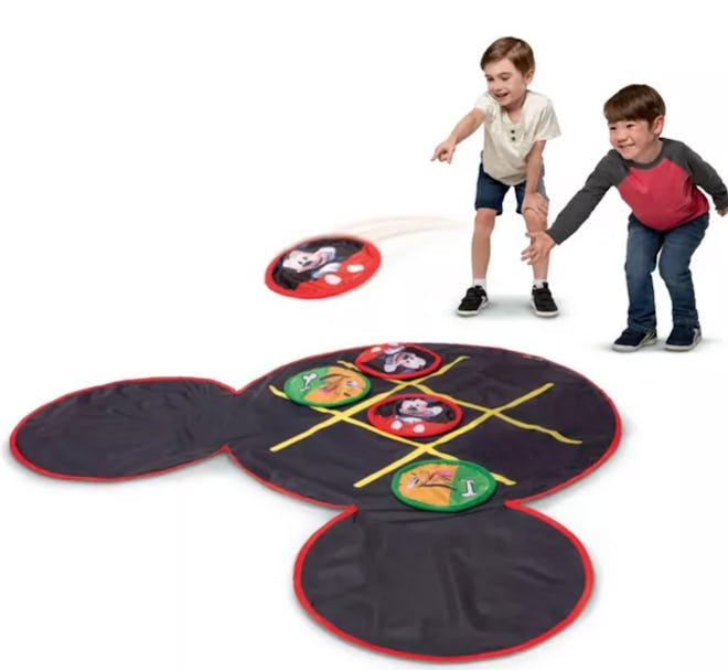 Image of a Mickey Mouse-shaped tic-tac-toe floor mat. Mat shown with kids tossing discs onto it.