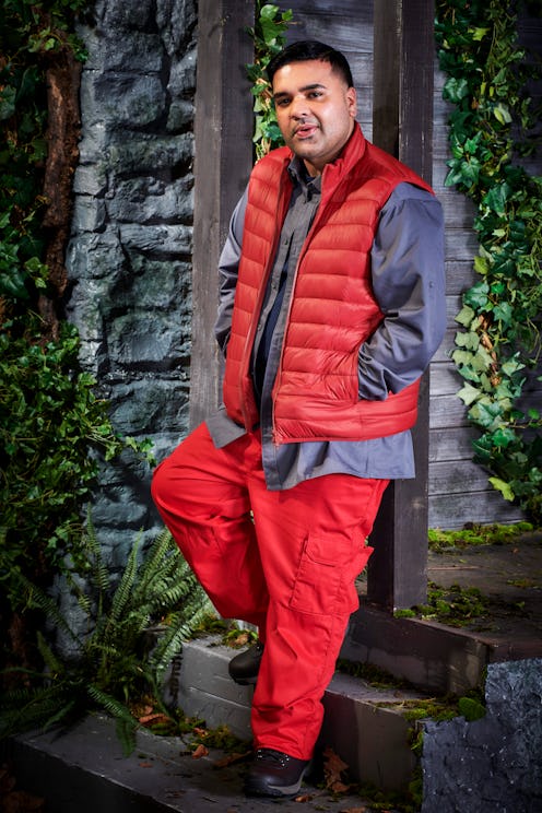 Naughty Boy poses in the I'm A Celeb castle wearing campmate clothing (red trousers grey and navy to...